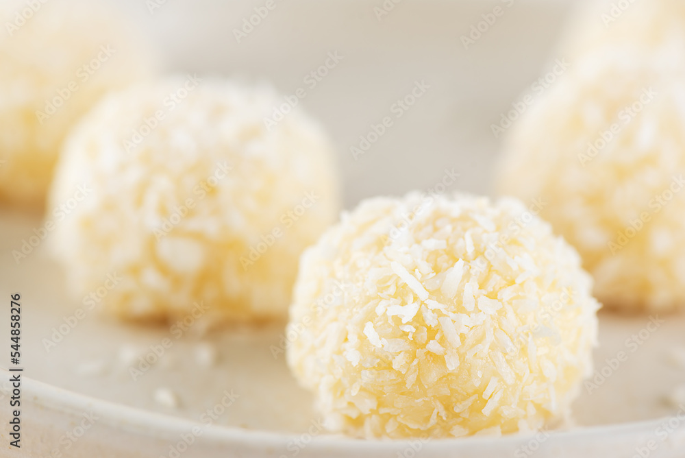 Candy truffles with coconut on a plate, closeup.