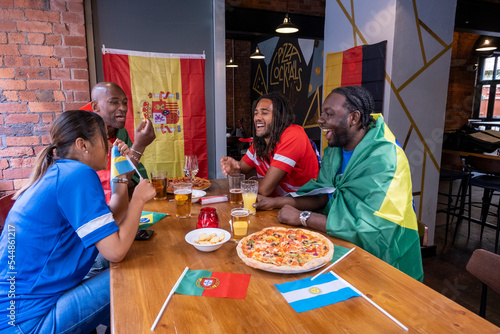 Friends dressed in national flags for world cup competition sitting in pub photo