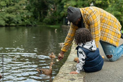 Father with daughter feeding duck on pond in park