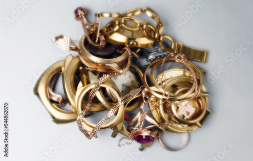 Old and broken gold and silver jewelry, coins, watches of gold, and gold-plated lies in a pile. In soft focus. Selective focus.