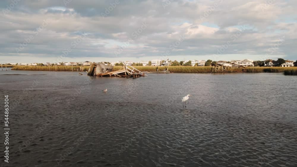 Heron walks in the foreground at sunset with push in revealing a broken dock after hurricane. Heron walks in the foreground at sunset with push in revealing a broken dock after hurricane.