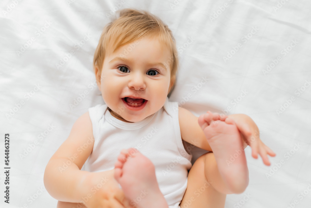 An Adorable baby girl in white sunny bedroom in the morning at home An Adorable baby girl in white sunny bedroom in the morning at home