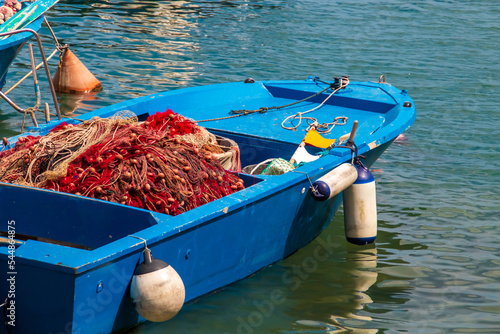 Redes y aparejos de pesca en Monopoli, Puglia, Italia. Barca azul fondeada en la dársena de Monopoli con las artes tradicionales de pesca. photo