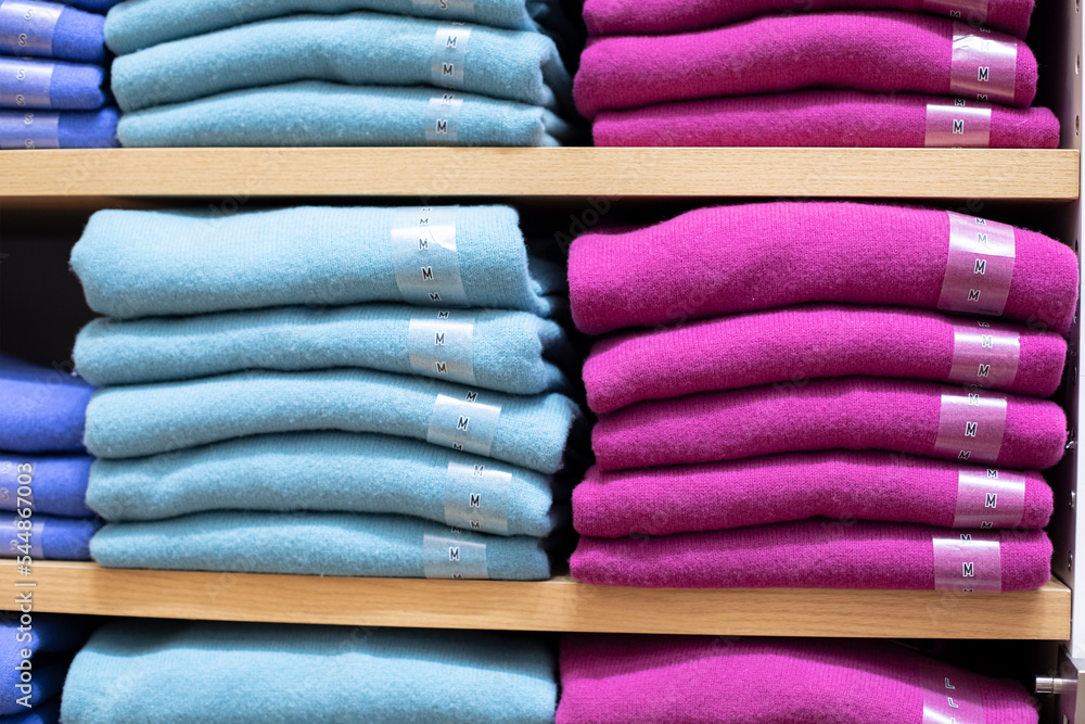 Blue pink magenta cashmere sweatshirt on the shelf, warm knitted sweater close-up, retail clothing background photography Blue pink magenta cashmere sweatshirt on the shelf, warm knitted sweater close-up, retail clothing background photography