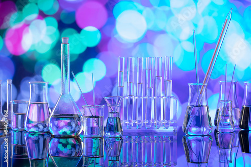 Laboratory investigations concerning test and medicine against covid. Glass tubes and beakers on blue bokeh background.