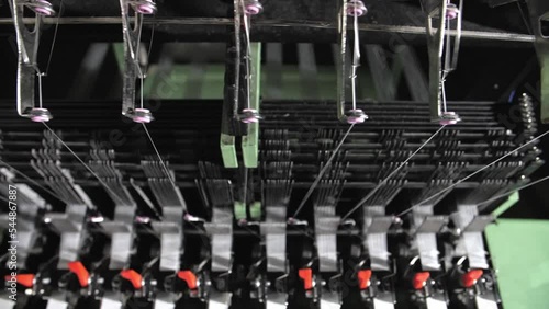Close up of textile machine in slow motion. Fibre thread lines on the weaving loom machine. A loom machine for clothing or woven clothes. Weaving machine for garment industry.