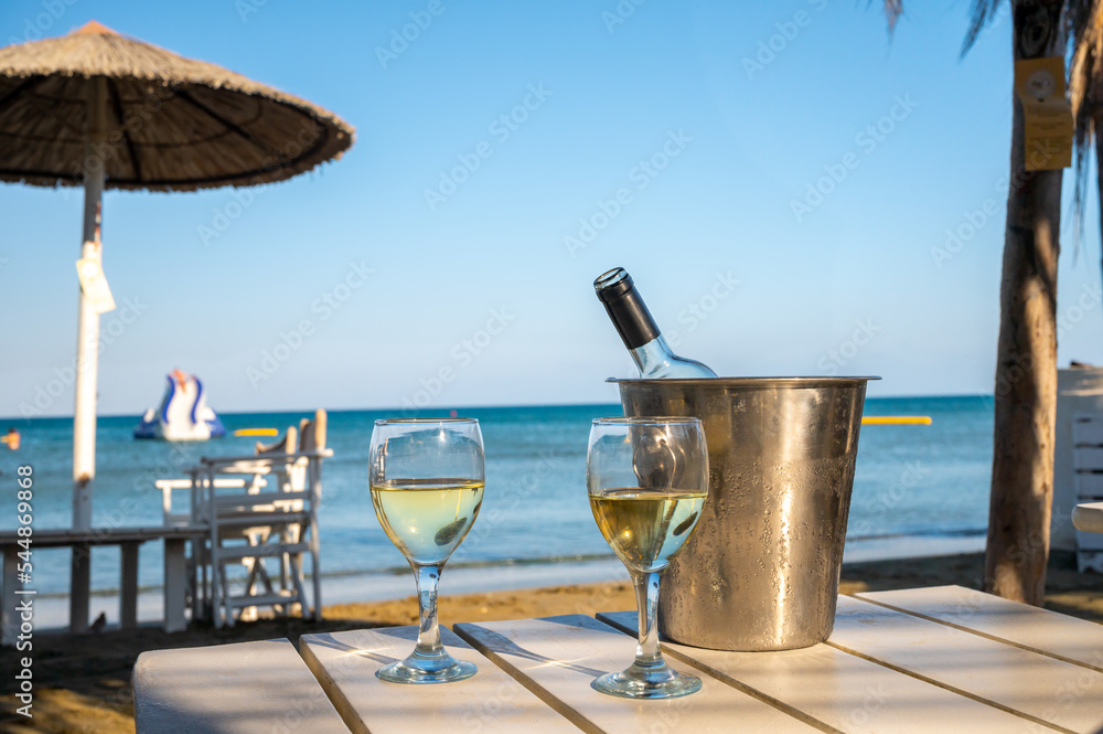 Drinking of cold white wine in beach bar, summer holidays, relax on sandy beach Drinking of cold white wine in beach bar, summer holidays, relax on sandy beach
