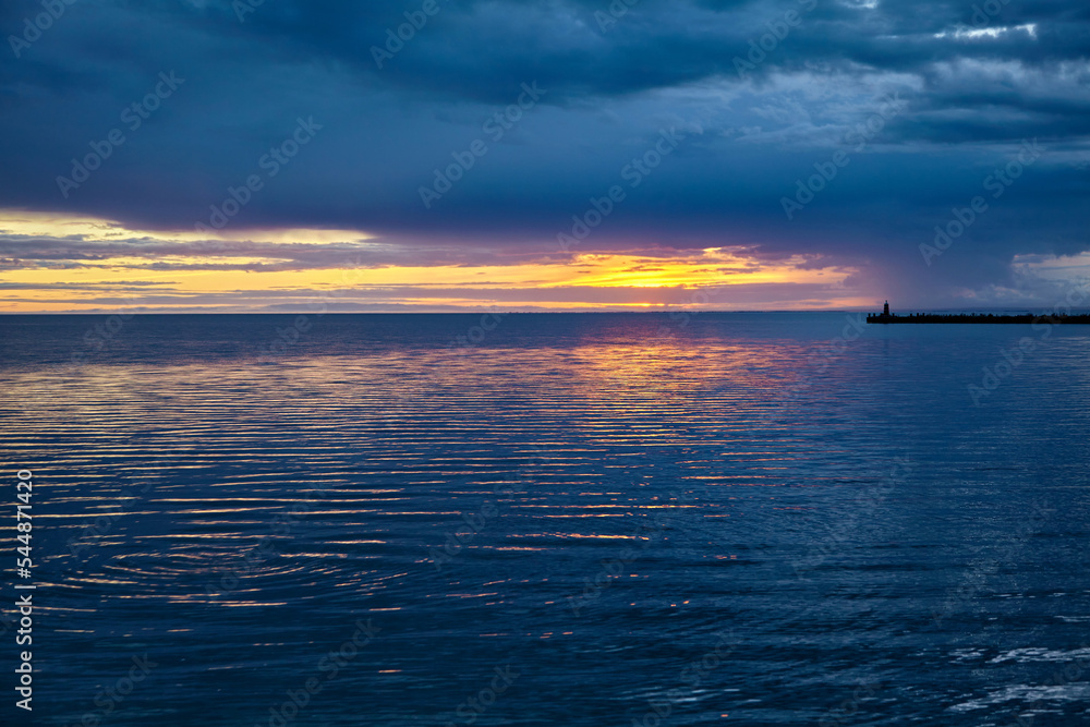 Obraz premium Sea pier with a lighthouse against the backdrop of the setting s