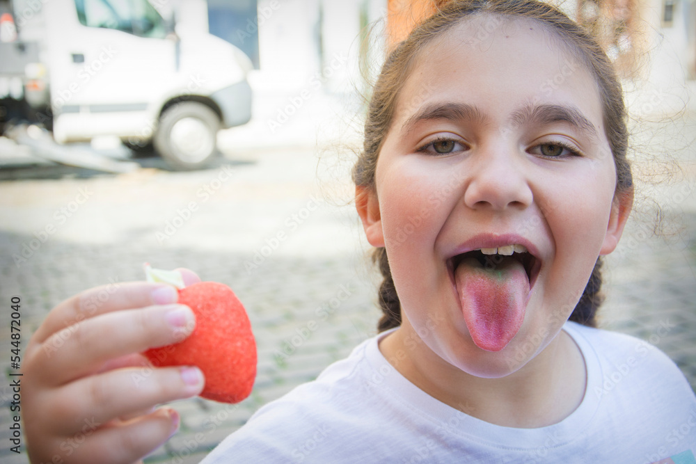 Foto de A teenage girl ate a candy and shows a colored tongue. The