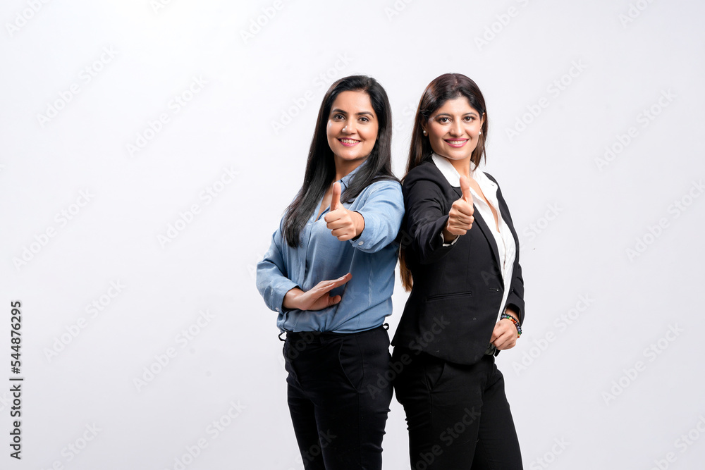 Two young indian business woman or employee showing thumps up on white background. Two young indian business woman or employee showing thumps up on white background.