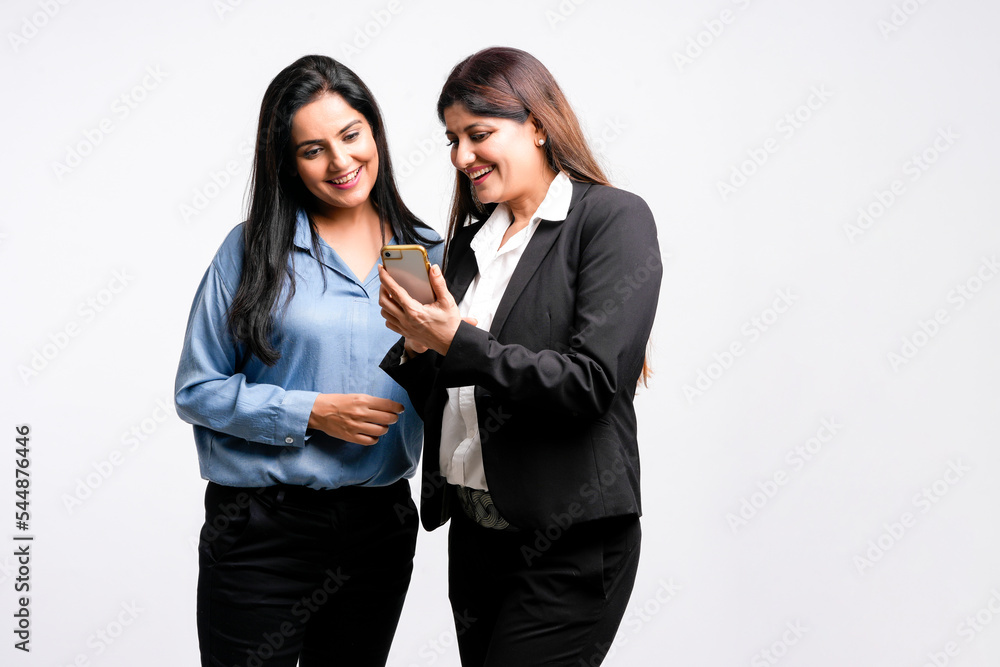 Two Young indian business woman or employee watching some detail in smartphone and discussing Two Young indian business woman or employee watching some detail in smartphone and discussing