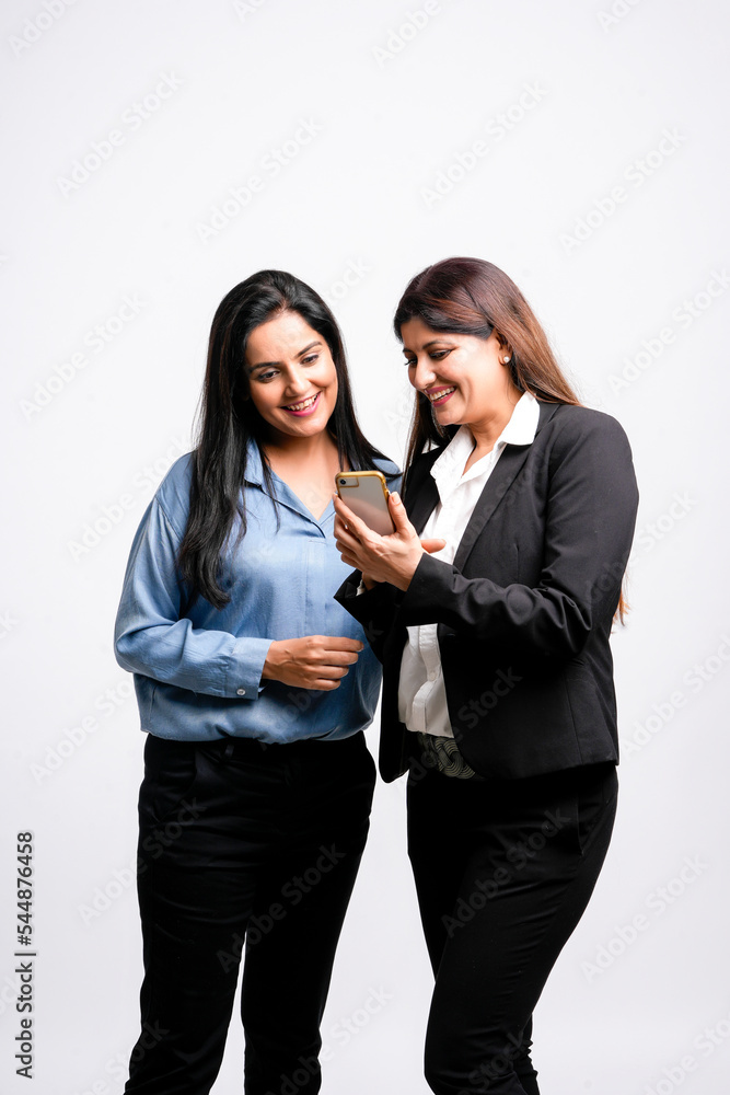 Two Young indian business woman or employee watching some detail in smartphone and discussing Two Young indian business woman or employee watching some detail in smartphone and discussing