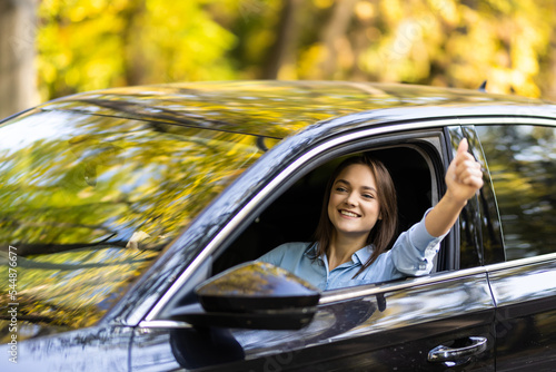 Foto Young woman inside a car driving in the street and gesturing thumb up