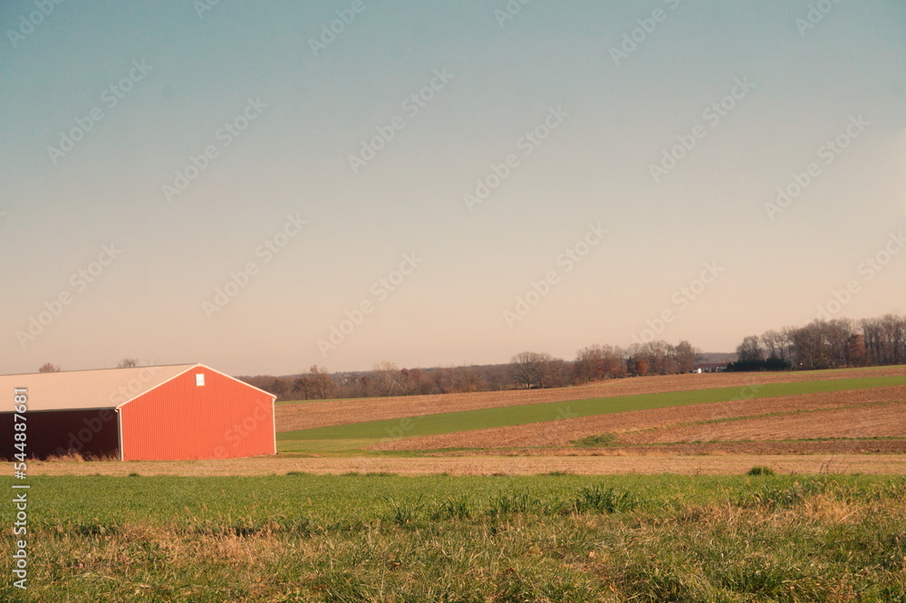 Corner of Red Farm Building and Alternating Green and Dry Fields with Blue Sunny Sky in Late Fall Corner of Red Farm Building and Alternating Green and Dry Fields with Blue Sunny Sky in Late Fall