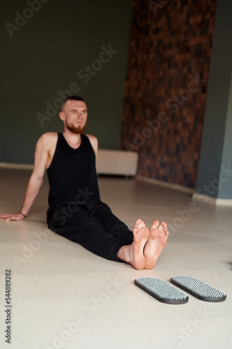 Selective focus. Mans legs after standing on sadhu board with sharp nails. Male relaxe after yoga practice sitting on the floor in studio indoors