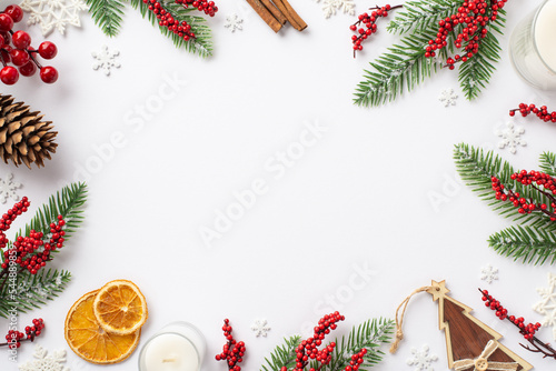 Christmas decor concept. Top view photo of fir branches mistletoe berries pine cone candles wooden ornament dried orange slices snowflakes on isolated white background with copyspace in the middle