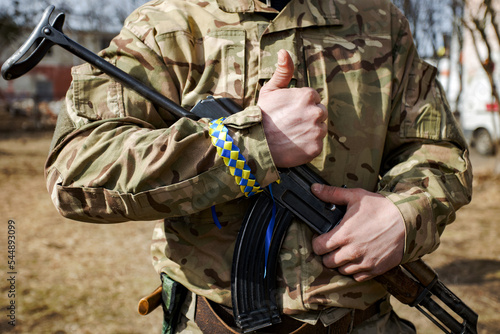 Valokuvatapetti The man in camouflage with yellow and blue ribbon wristlet on his hand holding a