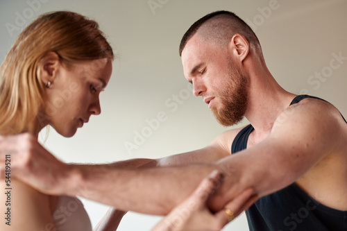 Practice of standing on nails. Woman helps man while stand on sadhu board with sharp nails indoors. Emotional male face. Concept on healthy lifestyle.