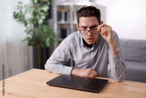 Confused man with laptop at desk