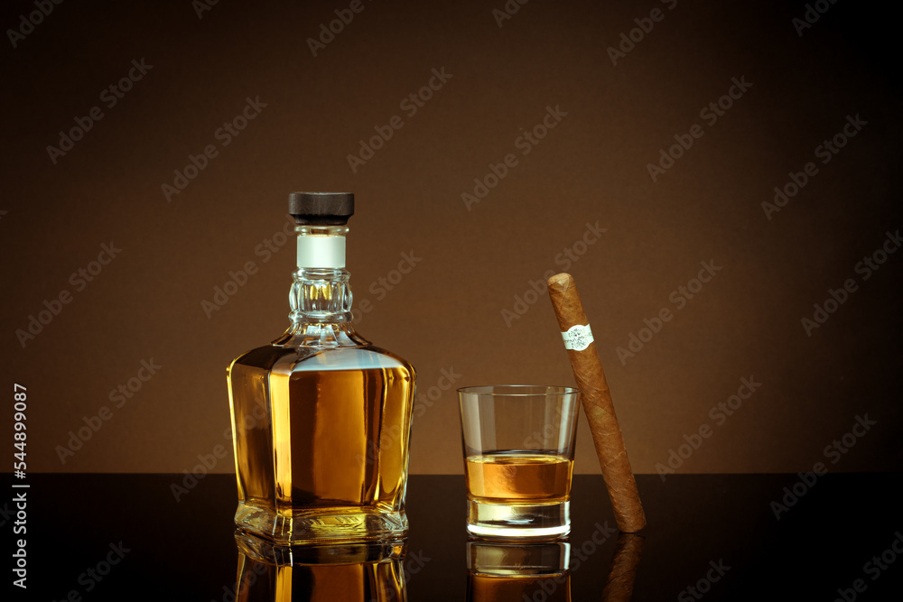 close up view of cigar, bottle of whiskey and glass on color back. close up view of cigar, bottle of whiskey and glass on color back.