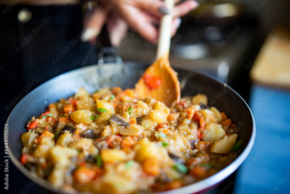 Woman cooking tasty vegetable stew in pan on kitchen