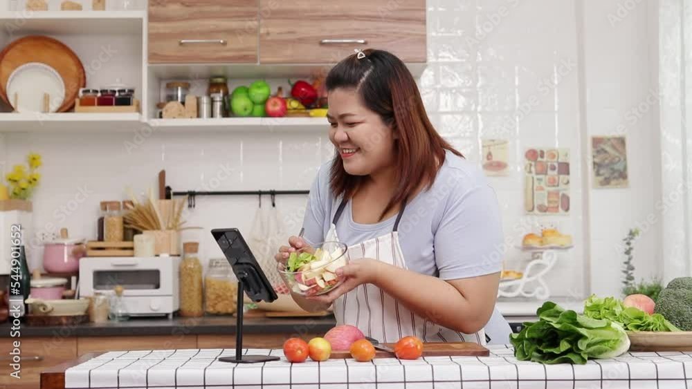 Fat Asian woman cooking in kitchen at home Happy cooking. Online video calls via smartphones. content creator on social media Fat Asian woman cooking in kitchen at home Happy cooking. Online video calls via smartphones. content creator on social media