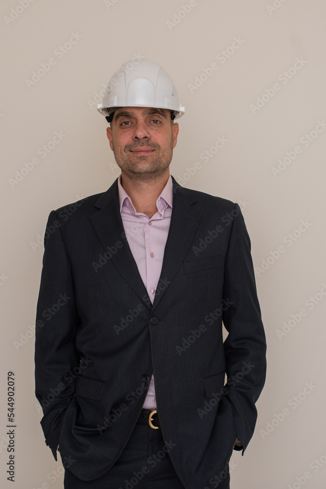 Portrait of a male architect or builder in a formal suit and helmet, a male foreman in a helmet looks at the camera on a gray background