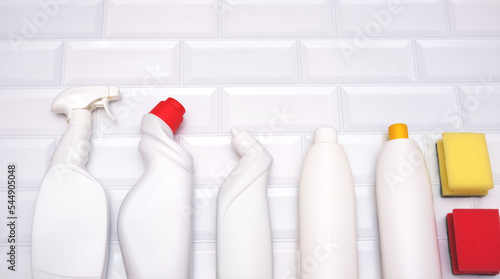 White bottles of cleaning products on a white brick background. view from above