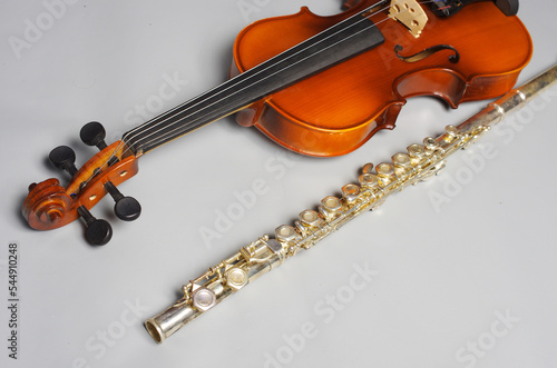 Violin and silver flute on a light background.