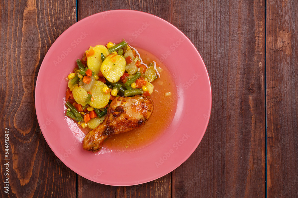 Baked chicken drumstick with vegetables in sauce and spices.