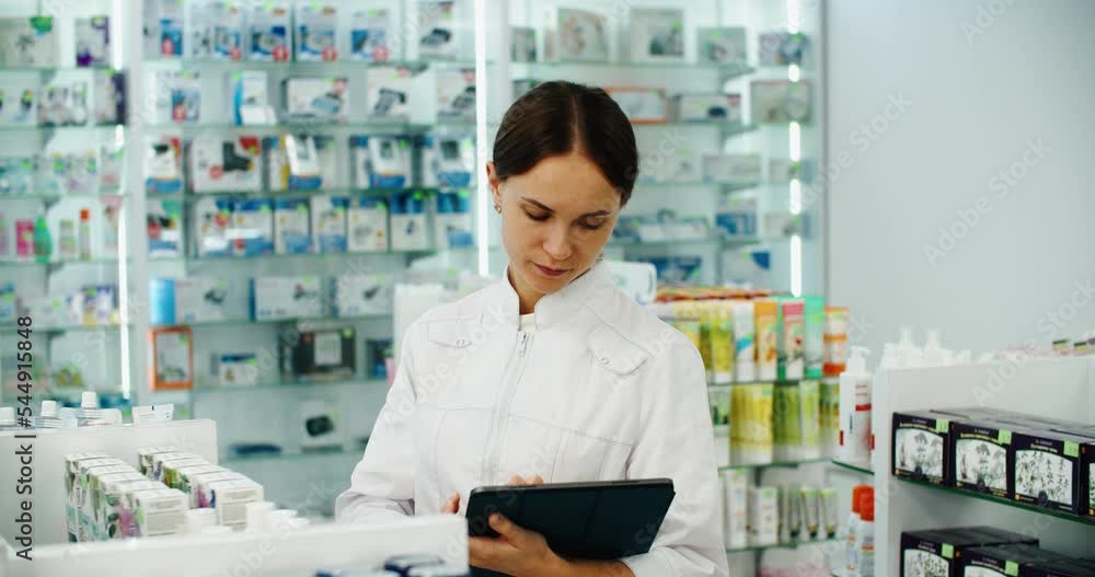 friendly pharmacist does an inventory at a provided and modern pharmacy. Portrait of a female doctor working in a pharmacy with a digital tablet. High quality 4k footage friendly pharmacist does an inventory at a provided and modern pharmacy. Portrait of a female doctor working in a pharmacy with a digital tablet. High quality 4k footage