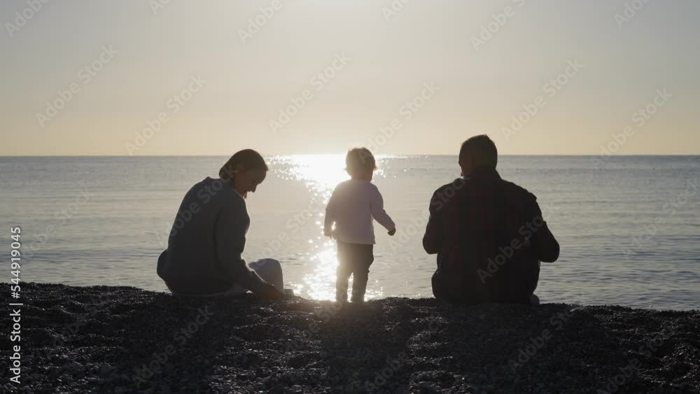 Happy young family walking on the beach into the sunset. High quality 4k footage Happy young family walking on the beach into the sunset. High quality 4k footage