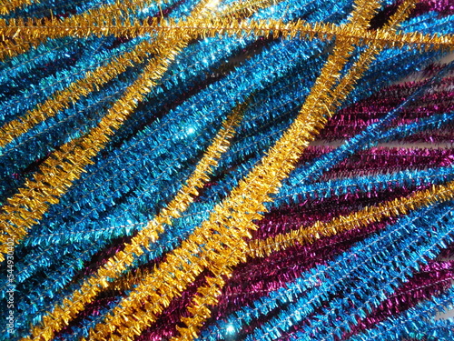 Shiny Christmas garlands (decorations, decor, shimmering wire for needlework), many different shades and sequins, shining in electric light.