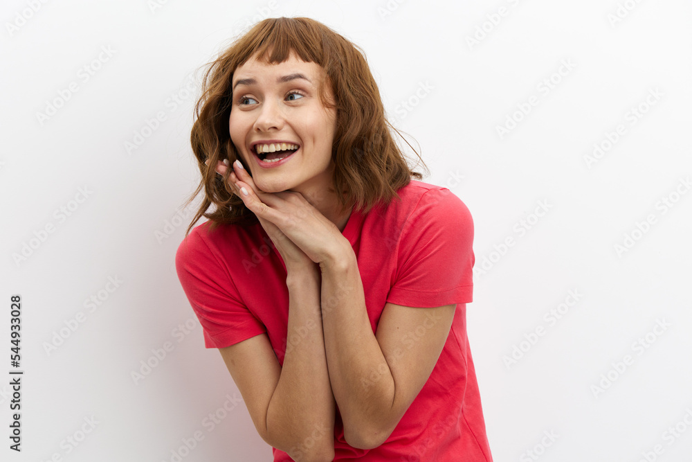 a happy, joyful woman with red hair stands on a white background, smiling broadly, holding her hands folded in her palms near her face a happy, joyful woman with red hair stands on a white background, smiling broadly, holding her hands folded in her palms near her face