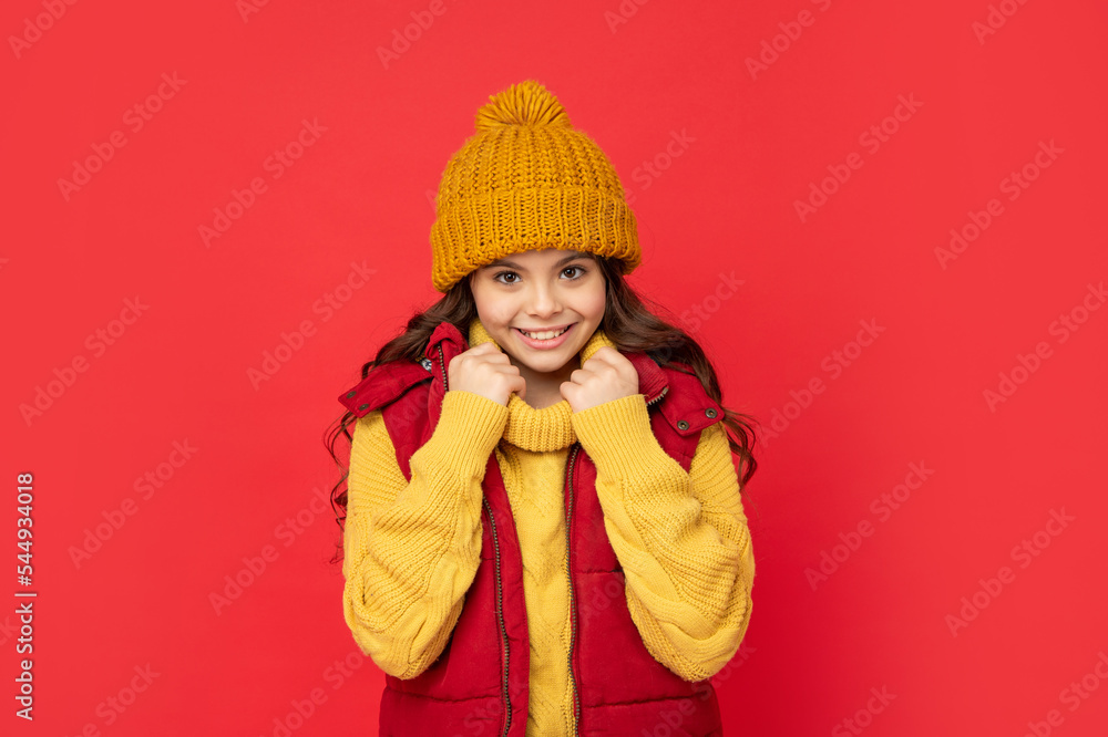 cheerful teen girl in knitted winter hat on red background, autumn cheerful teen girl in knitted winter hat on red background, autumn