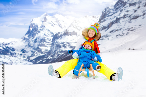 Mother and baby on sleigh ride. Winter snow fun.