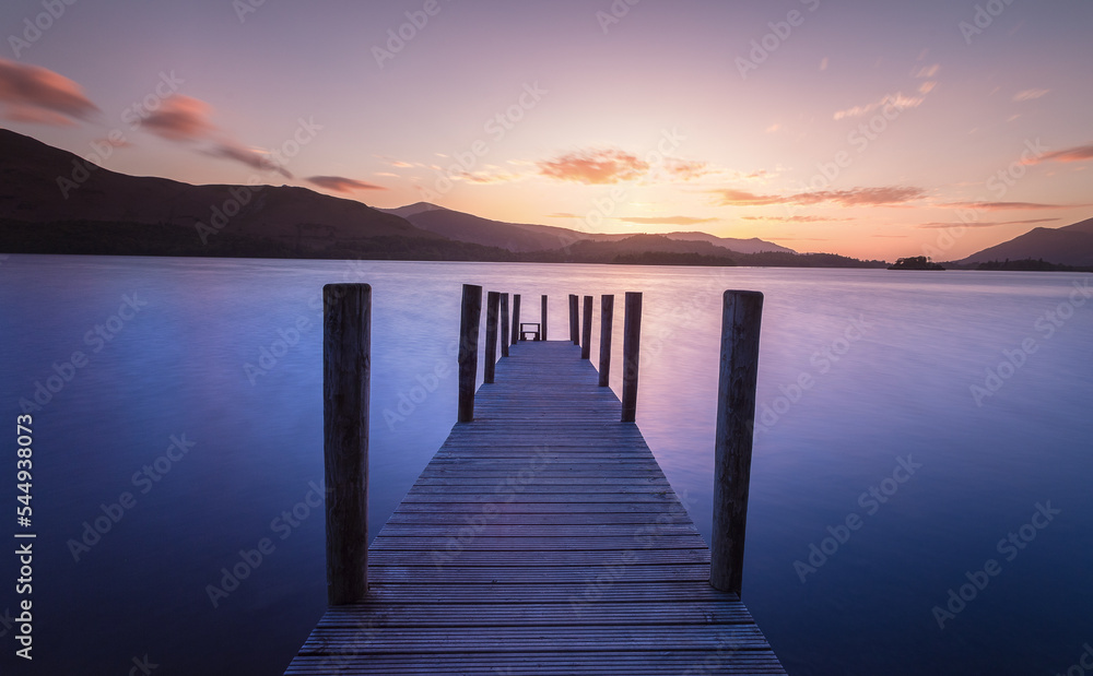 Long exposure post sunset of wooden jetty leading into a lake.  Lake District Uk. Feelings of calm and relaxation