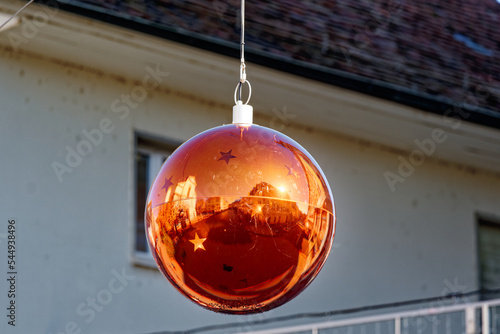 Big golden Christmas bauble with reflections hanging on rope at the old town of Olten on a blue cloudy autumn day. Photo taken November 10th, 2022, Olten, Switzerland. photo