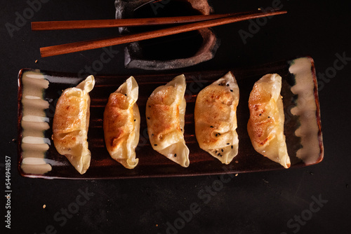 Gyozas famous Japanese steamed food, delicious Japanese food with black background and decorated with leaves and a wicker basket, for oriental and Asian food restaurant.