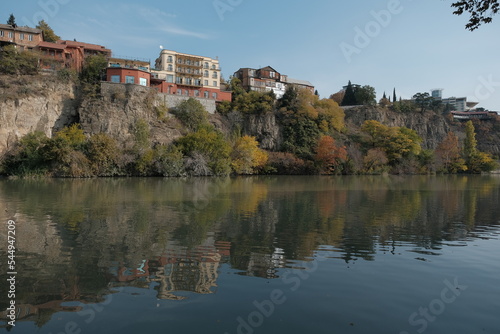 reflection of autumn colors in the river. rocky river bank. yellow autumn trees and houses are reflected in the water