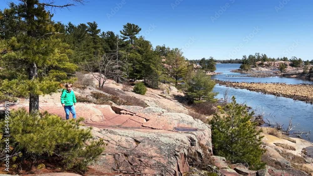 Little boy playing on rock beside river against clear sky on sunny day Little boy playing on rock beside river against clear sky on sunny day