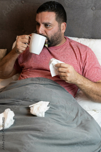 Hombre de mediana edad en cama enfermo con síntomas de gripe
 photo
