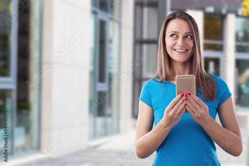 Happy young woman standing at city street background