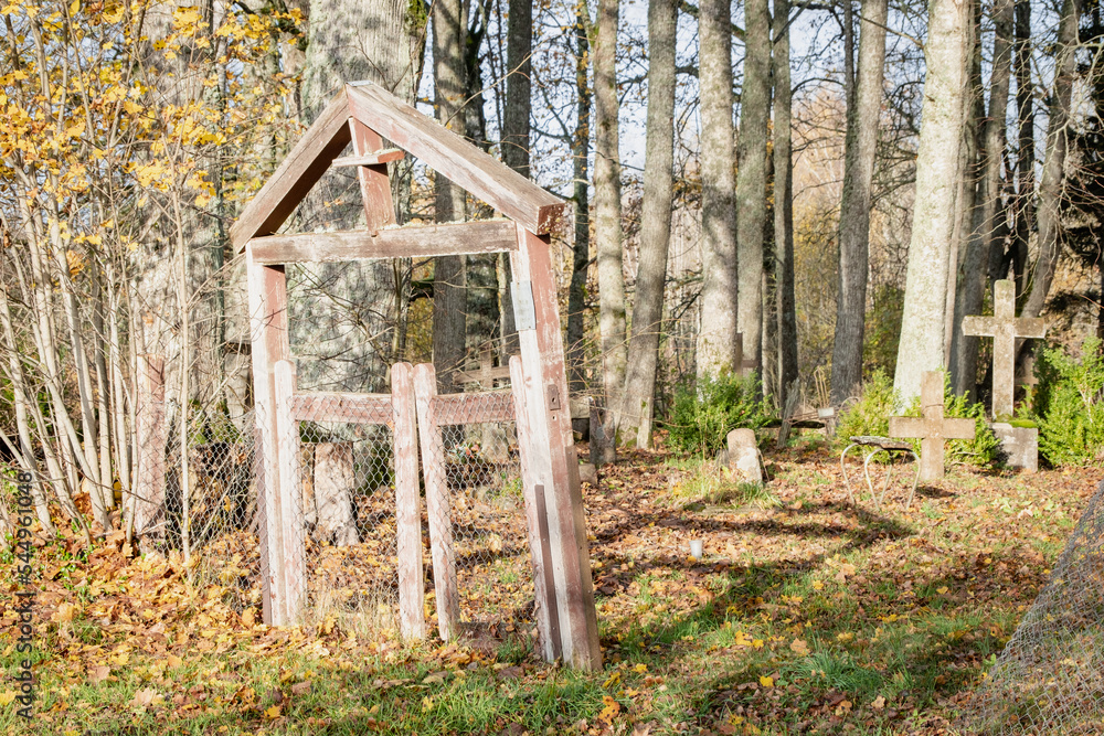 old abandoned wooden cemetery gate in Latvia countryside. Graveyard on hill. Damaged fence. Christian crosses on burial ground	