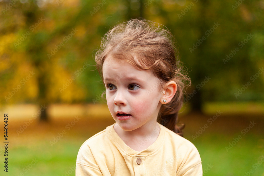 Lovely cute red-haired little girl in the autumn park outdoors. Lovely baby in front of falling leaves Lovely cute red-haired little girl in the autumn park outdoors. Lovely baby in front of falling leaves