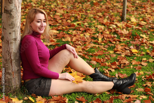 Young woman sitting on the grass in autumn park