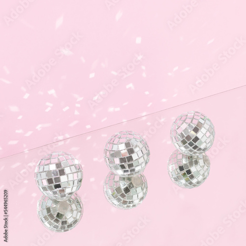 Three shiny disco balls with mirror reflection against bright pink background. Minimal holidays celebration party creative concept. Retro 80s or 90s disco aesthetic.