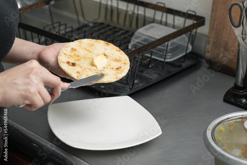 detailed view of a girl's hands buttering an arepa. woman preparing a typical colombian breakfast.
