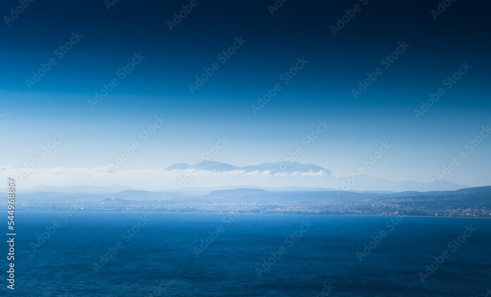 View of seascape and mountain against blue sky