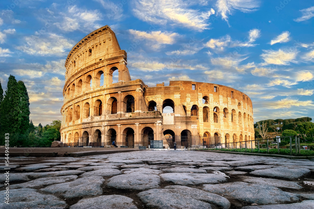 Colosseum at sunset in Rome, Italy. Low angle view of the main facade of the Colosseum and, in the foreground, the ancient paving in polished stone slabs.
